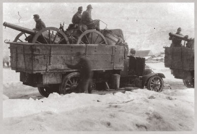 Open truck carrying canon and soldiers in winter