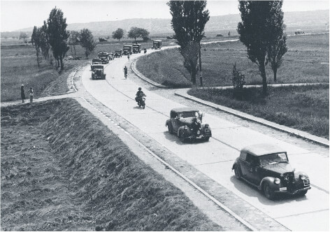 Procession of cars and trucks on a road near Lake Balaton that depicts the invasion of Yugoslavia in 1941