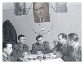 Hungarian policemen meeting under a large portrait of Rákosi