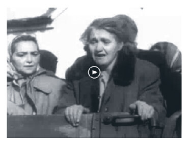 Looped video footage showing an older woman with other Hungarians in the back of an open truck, crying and looking anguished