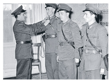 An officer adjusts a policeman’s uniform