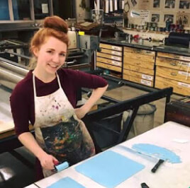 Dana standing at a counter in a printmaking studio.